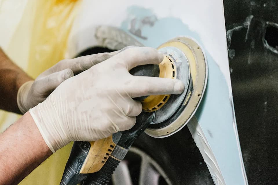 Schleifen einer grundierten Karosseriefläche mit der Schleifmaschine